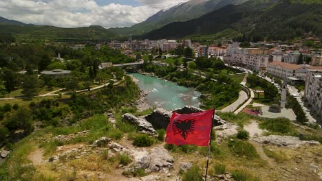 an albanian flag on top of a mountain in berat