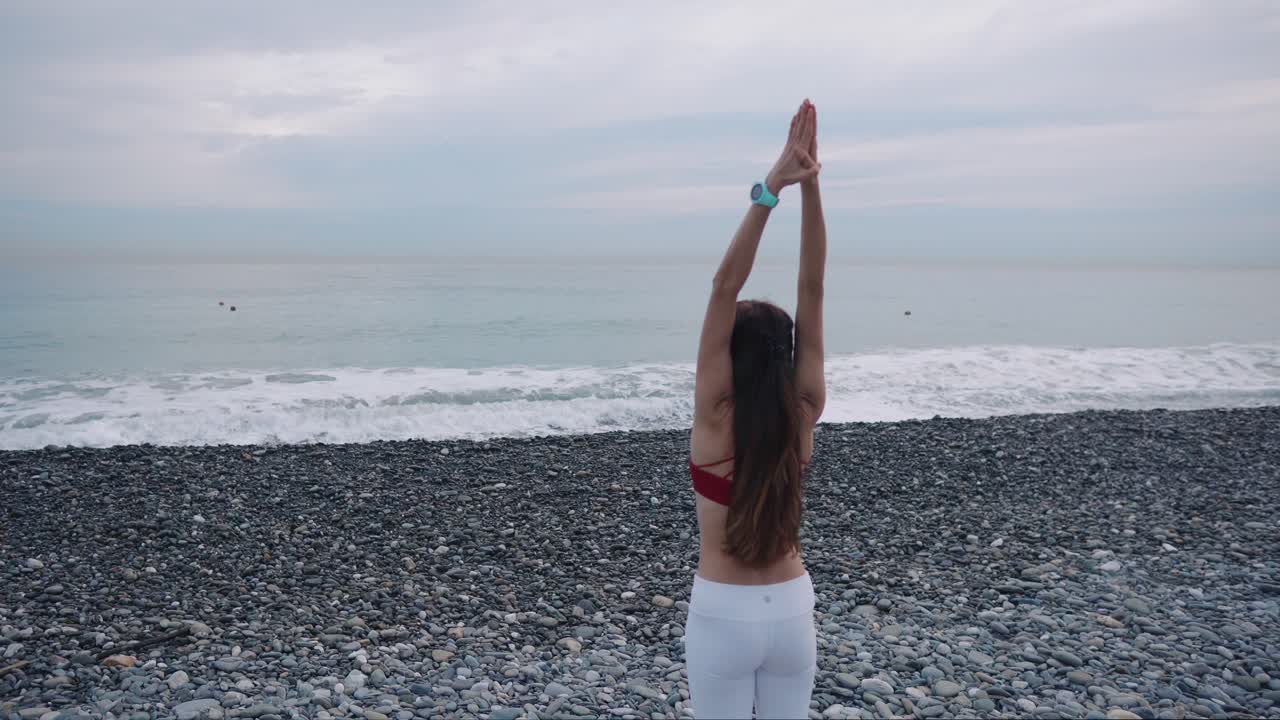 mujer practicando yoga en la playa