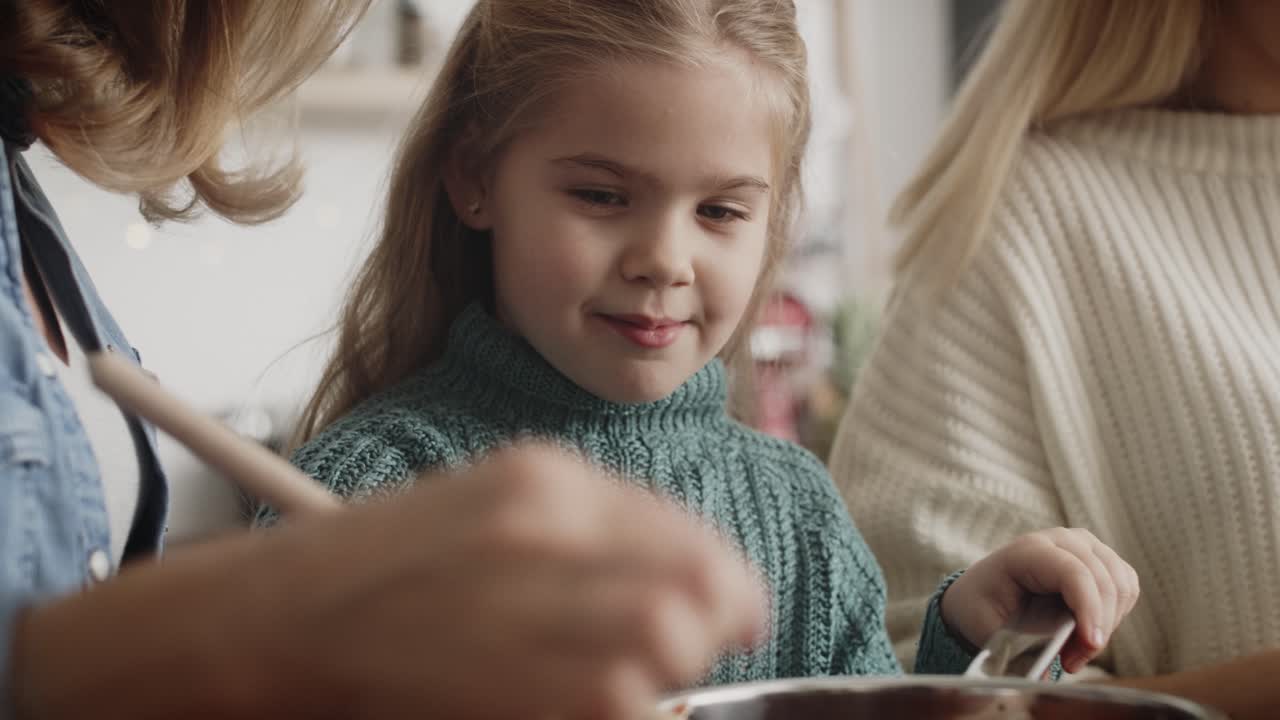 Video in primo piano di bambina che cucina con madre e nonna