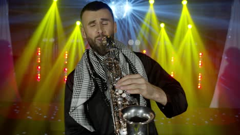 live performance of saxophonist man with saxophone, dancing on concert musician stage with lights