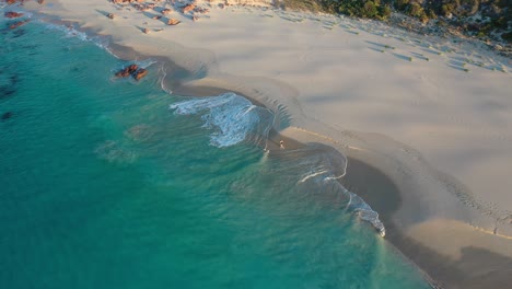 Drone-Aerial-View-of-Person-Running-on-White-Sand-Beach-by-Turquoise-Ocean-Water-After-Sunset,-Tracking-Shot