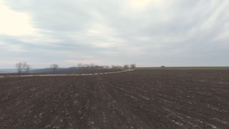 Vista-Panorámica-De-Una-Tierra-De-Cultivo-Junto-A-La-Carretera-Contra-El-Cielo-Nublado