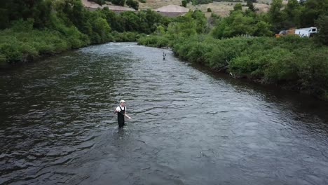 drone shot rotating around a man fly fishing in the provo river in the mountains of utah