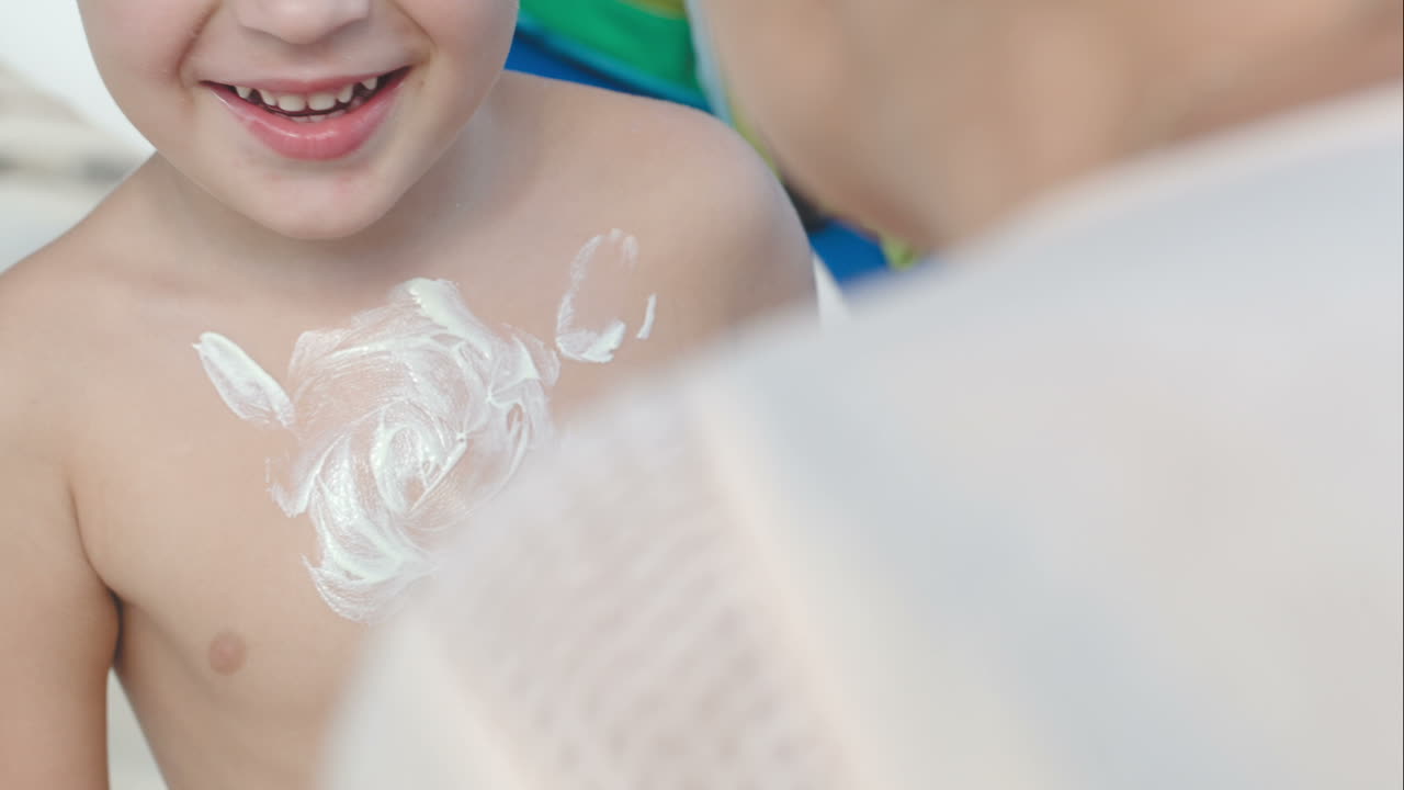 Mother drawing sun on sons chest with sunscreem cream