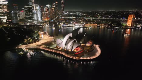 night aerial of sydney opera house in australia and city centre with illuminated skyscrapers.