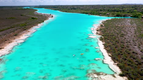 descending drone shot of kayakers in clear blue waters at bacalar mexico