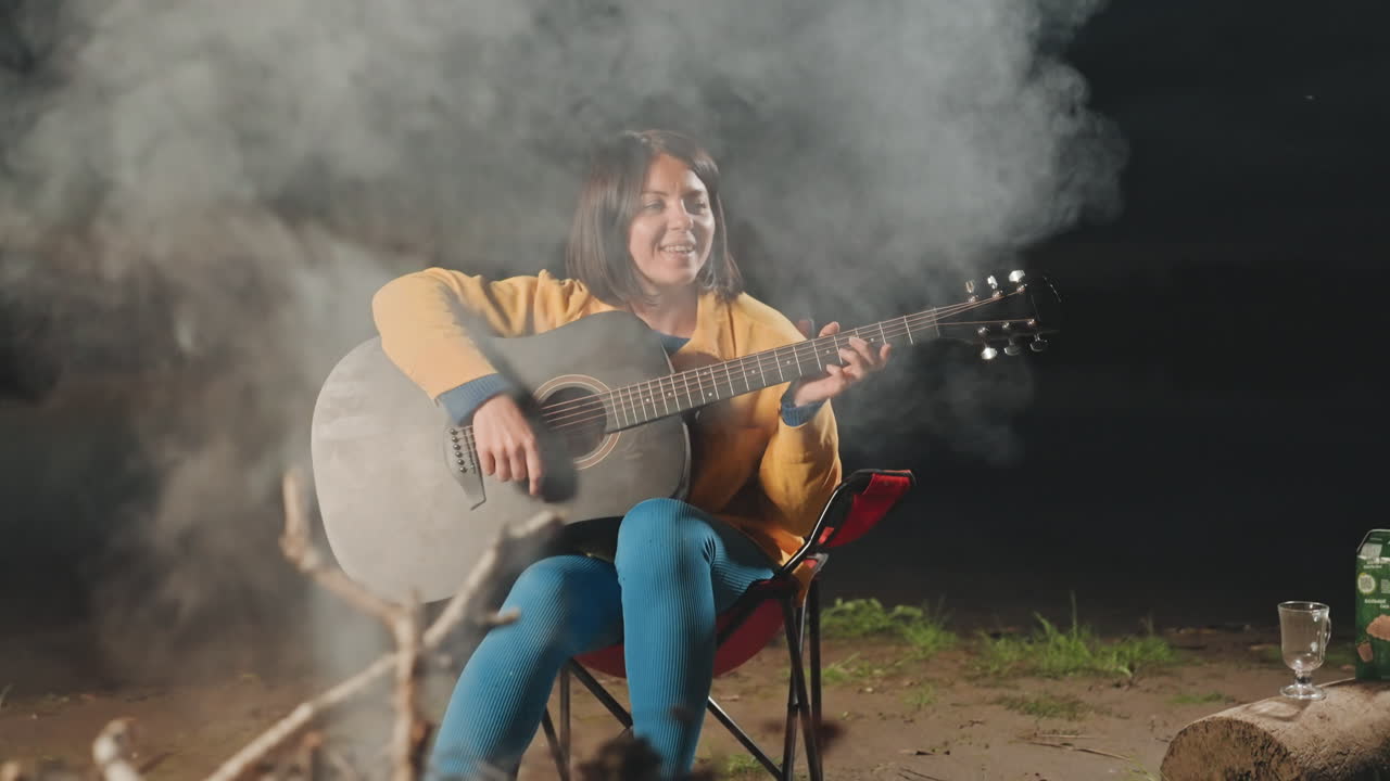 Serata ricca di melodie allegre e fiamme vivaci. La notte echeggia di suoni gioiosi mentre una donna fa una serenata attorno al falò. Risate e canti armoniosi animano la serata accanto al fuoco luminoso e scoppiettante.