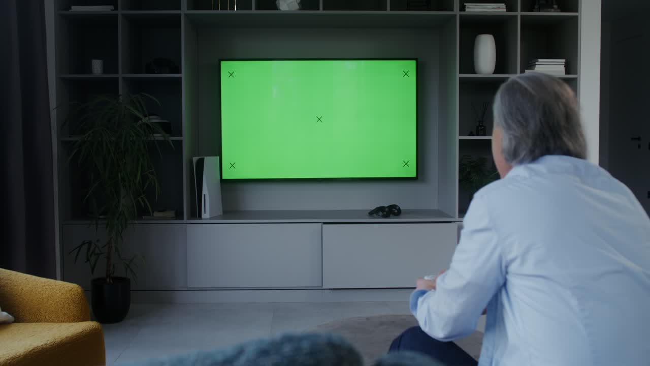 Man playing video games on green screen TV