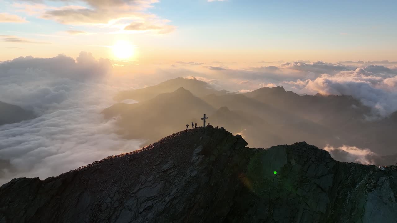 Mountaineers standing on a summit in the Austrian Alps during sunrise