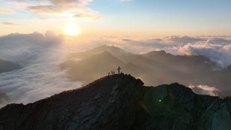 mountaineers standing on a summit in the austrian alps during sunrise