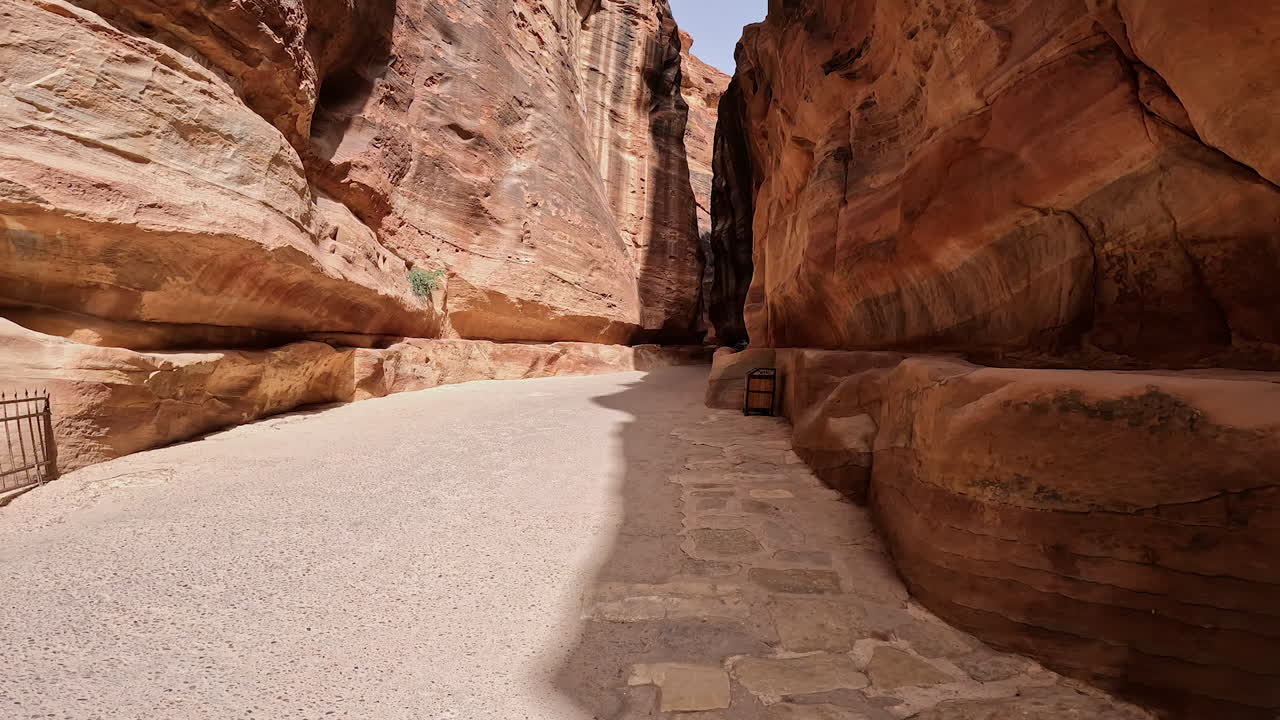 Walking along the road in the Al Siq Canyon in Petra, Southern Jordan, West Asia. Low angle view at the amazing sandstones leading to ancient city.