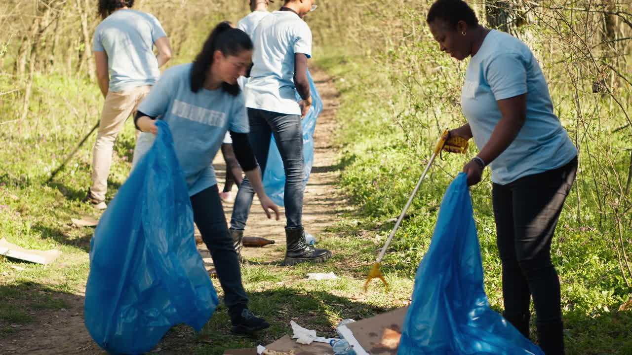 Group of diverse volunteers collecting rubbish from the woods and recycling