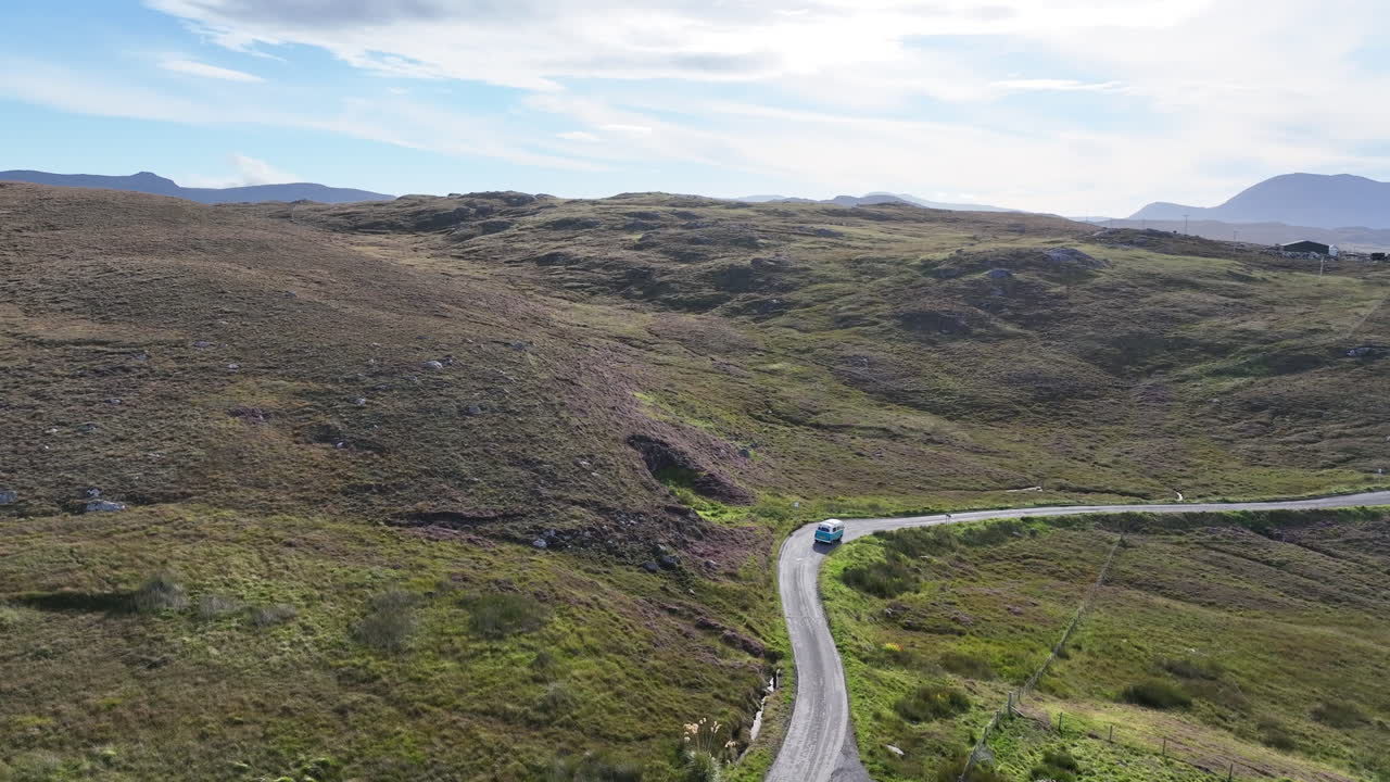 Drone captures a blue camper van departing a small cottage in the Scottish Highlands, heading onto the North Coast 500. A cinematic shot showing the freedom and solitude of remote Scottish travel