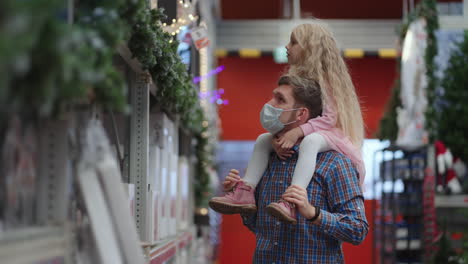 dad-and-daughter-choose-decorations-and-garlands-with-toys-for-Christmas-trees-and-at-home-in-the-store.-Christmas-garlands-and-decor