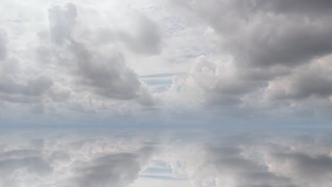 futuristic background consisting of time lapse clip of white fluffy clouds over blue sky and their reflection, video loop