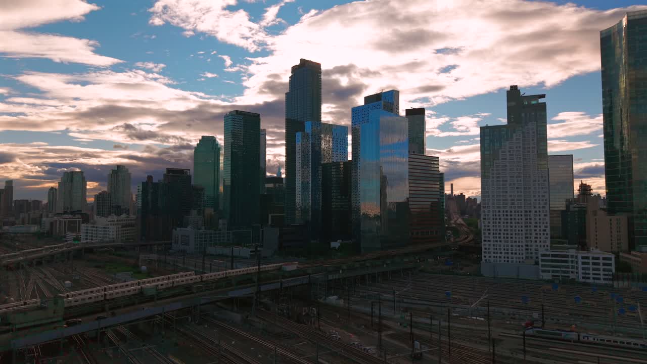 An aerial view of Long Island City, NY with skyscrapers in Queens. Taken during a cloudy evening over the Sunnyside Yard and Facility. The camera dolly in slowly.