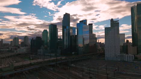 an aerial view of long island city, ny with skyscrapers in queens. taken during a cloudy evening over the sunnyside yard and facility. the camera dolly in slowly.
