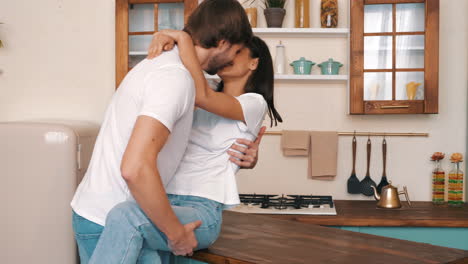 una pareja besándose en la cocina.
