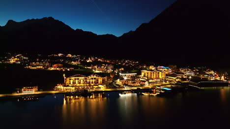 pertisau village with illuminated lights at night in austria - aerial drone shot