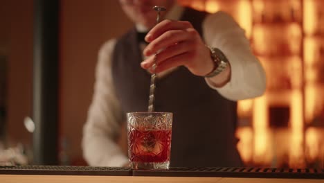 bartender manos haciendo y revolviendo cóctel negroni