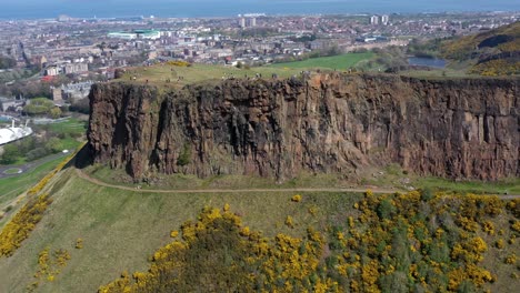 Panning-Around-The-Crags-at-Arthur's-Seat,-near-Holyrood-Parliament,-with-Tourists-Walking-|-Edinburgh,-Scotland-|-4K-at-30-fps