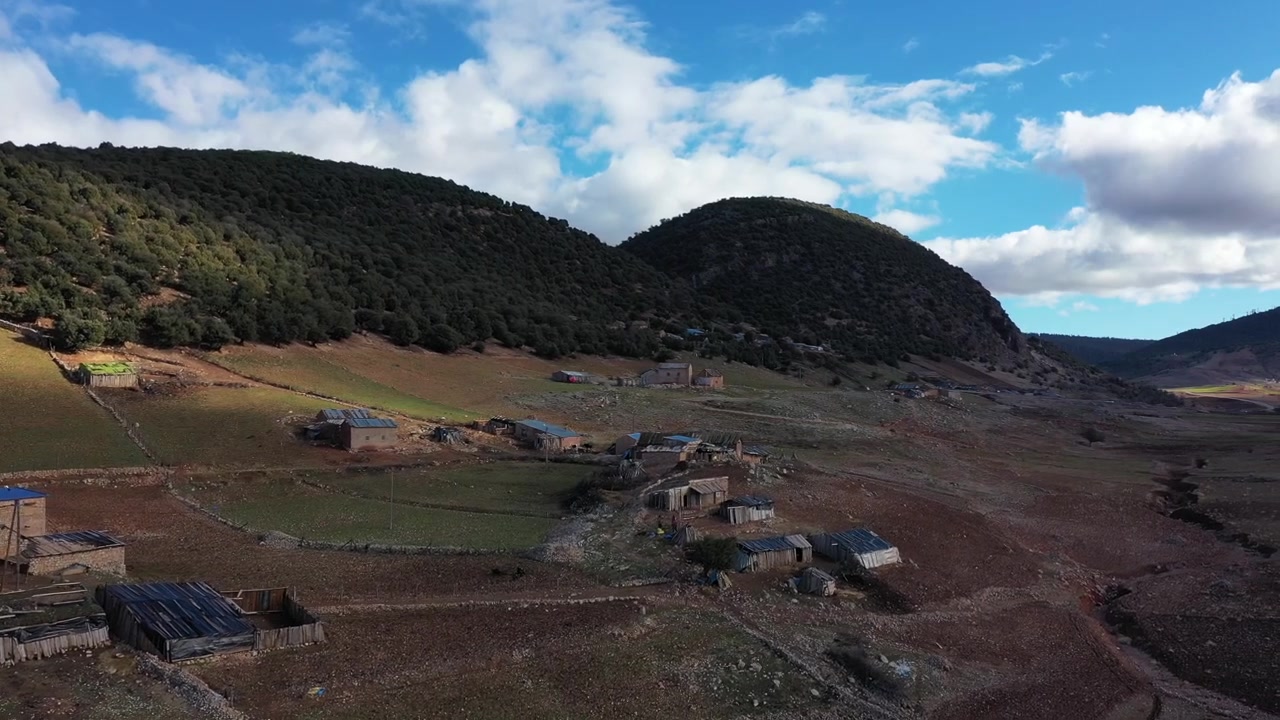 Filmisk droneudsigt fra luften af en landlig bjergbebyggelse omgivet af grønne bakker i Mellem Atlas, Marokko, ideel til rejse-, landskabs- og dokumentarprojekter.
