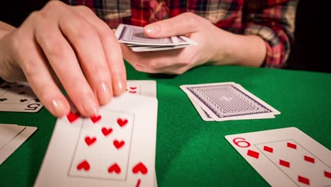 close up of female hands holding cards and playing solitaire