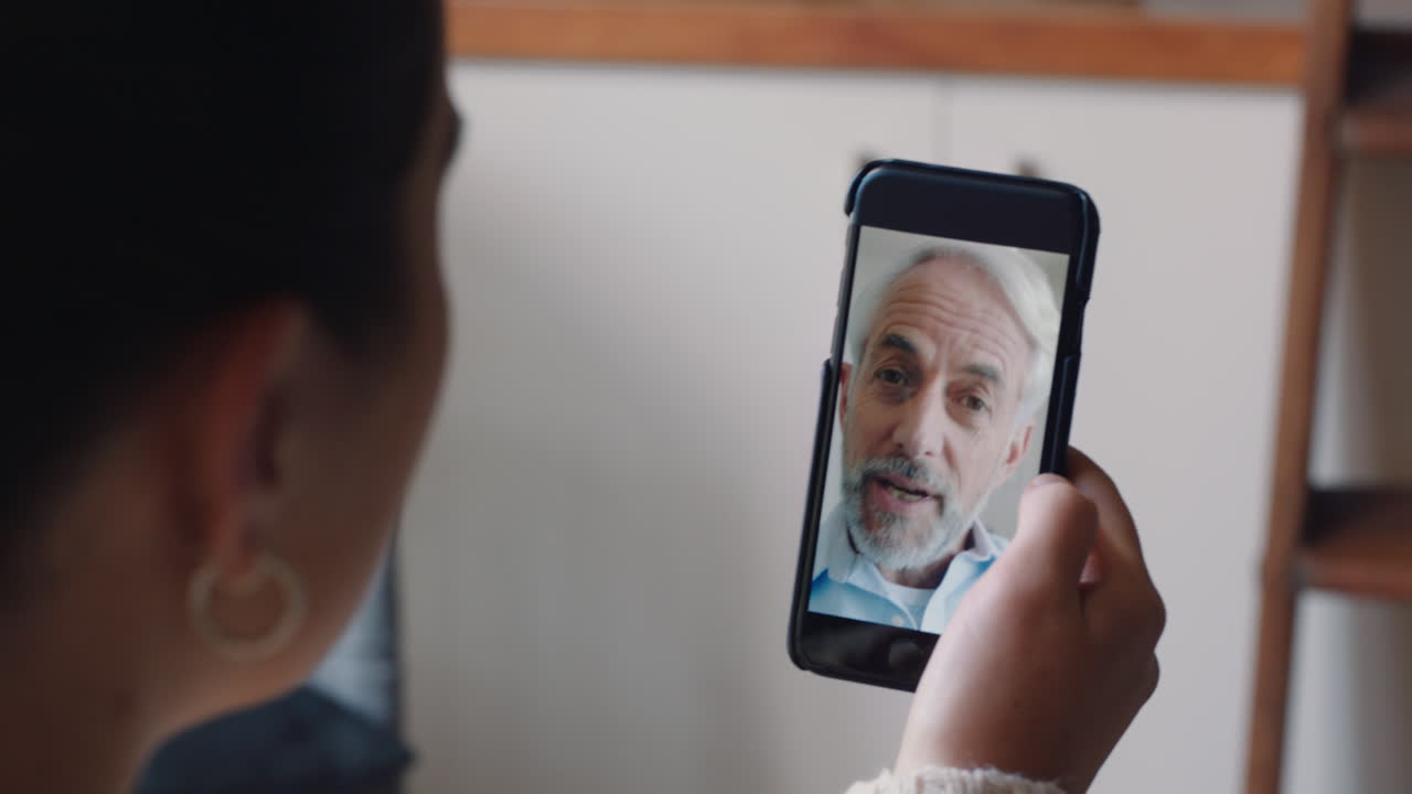 mujer joven teniendo video chat usando teléfono inteligente en casa hablando con el abuelo mostrando el estilo de vida de compartir apartamento disfrutando de la comunicación por teléfono móvil