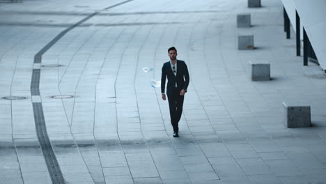 man walking in stylish suit at street. businessman throwing papers outdoors