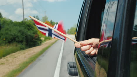 hand with norway flag in a car window travel scandinavia concept