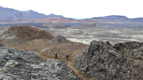 Icelandic-lava-terrain,-hikers-explore-volcanic-landscape