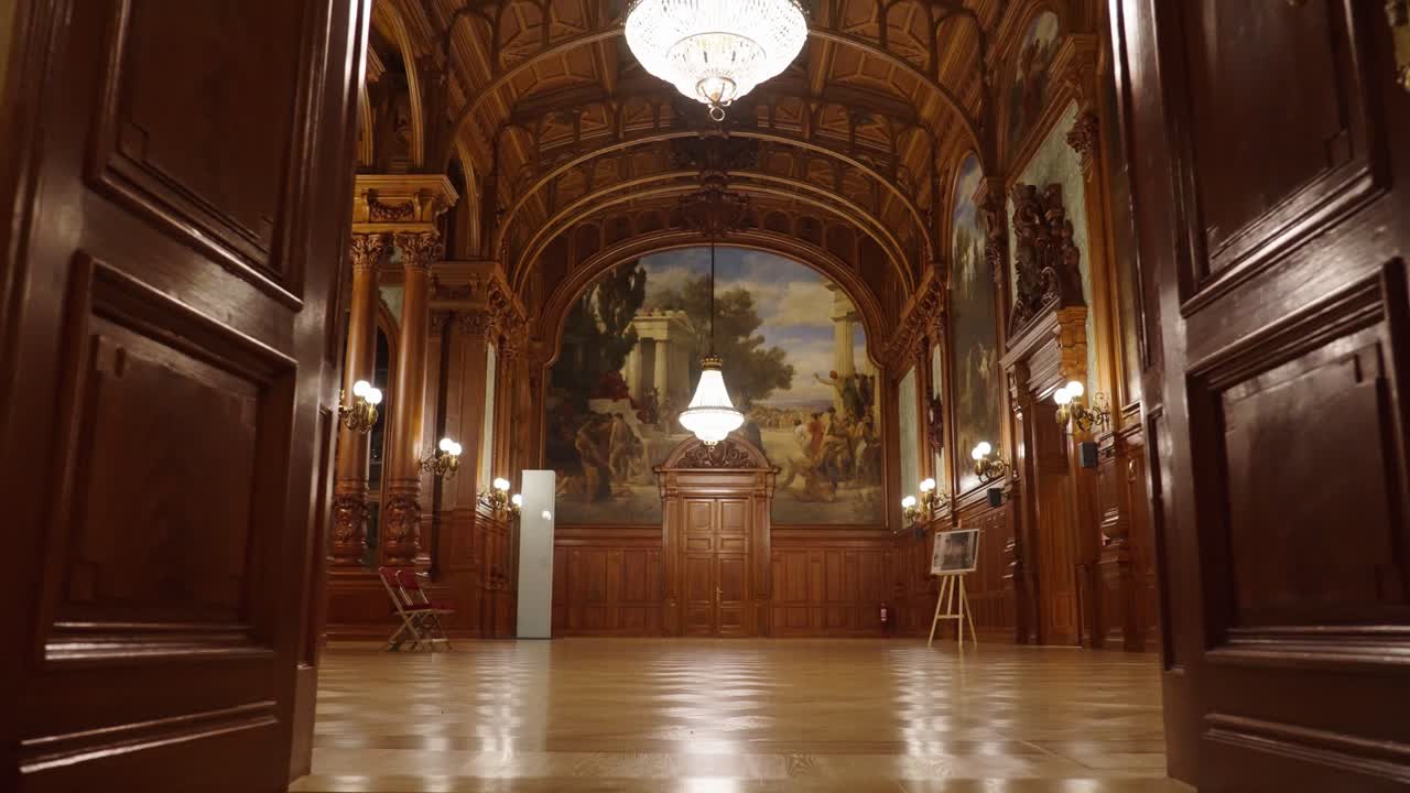 entrando en el salón de baile de madera con pinturas y candelabros colgados del techo