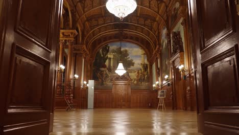 entrando en el salón de baile de madera con pinturas y candelabros colgados del techo