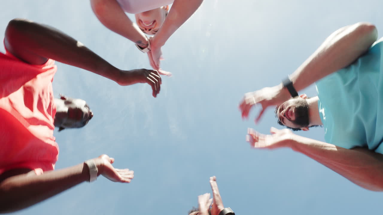 Mangfoldig gruppe venner klapper hænder i fejring under blå himmel