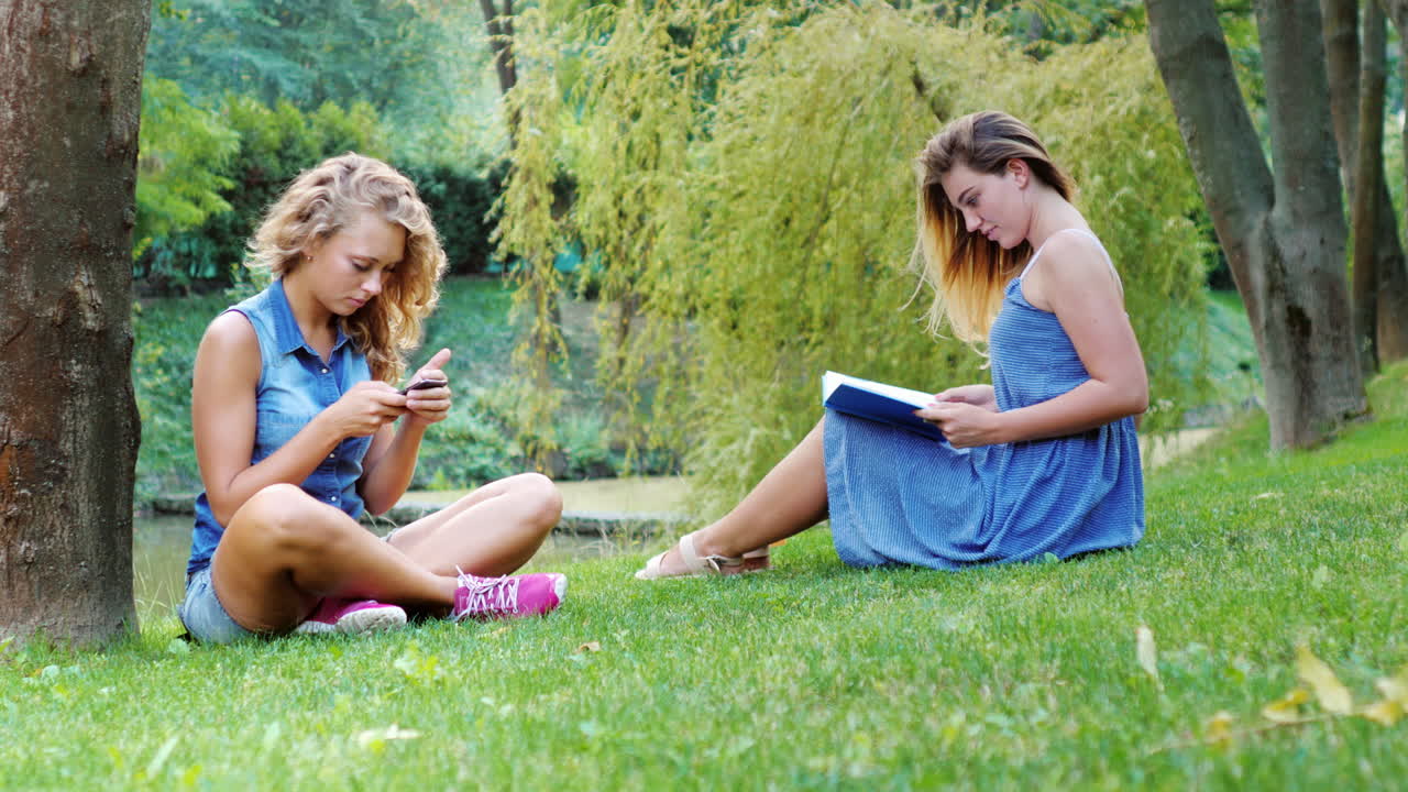 두 친구는 푸른 잔디에 앉아 공원에서 휴식을 취하다