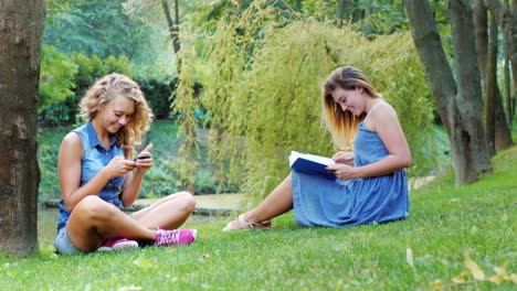 two friends relax in the park sitting on the green grass