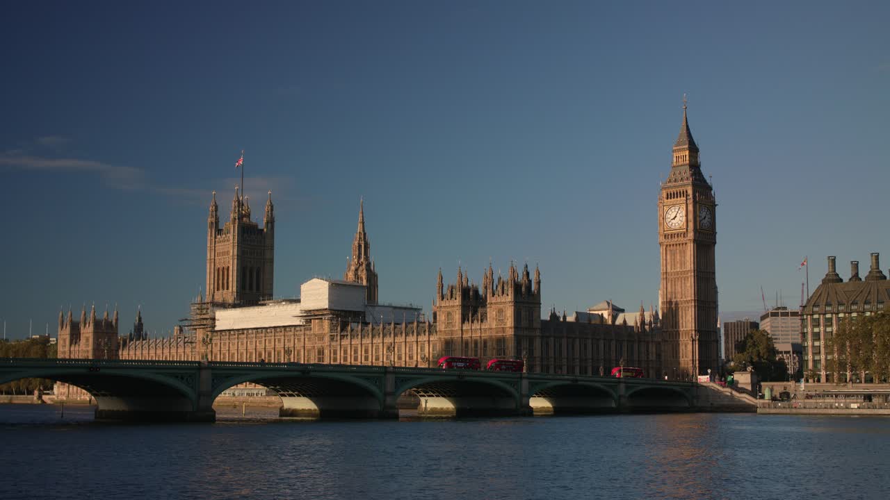 Wide view captures Westminster Bridge over the River Thames with the Houses of Parliament and Big Ben, sunlight reflecting on the water, iconic London architecture under a bright sky
