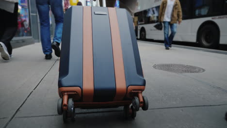 a tourist with a bag on wheels goes through the streets of manhattan in the frame you can see only t