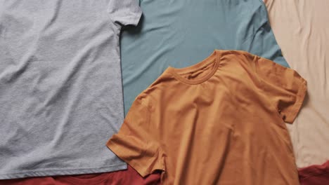 Video-of-flat-lay-of-multi-coloured-t-shirts-with-copy-space-on-white-background