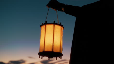 silhouette of a historical medieval character with cloak lantern at sunset sky