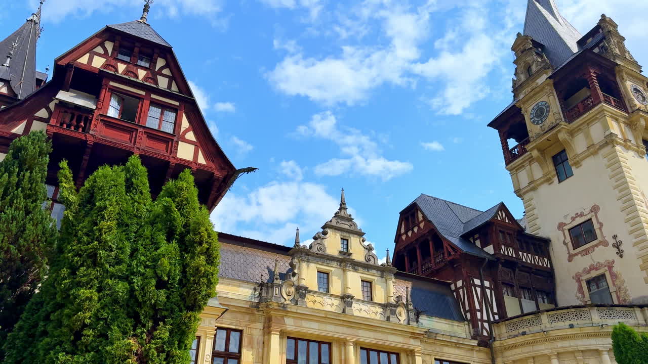 Main facade of Peles Castle in Romania. Historic main facade and tower of Peles Castle with spire and blue sky above