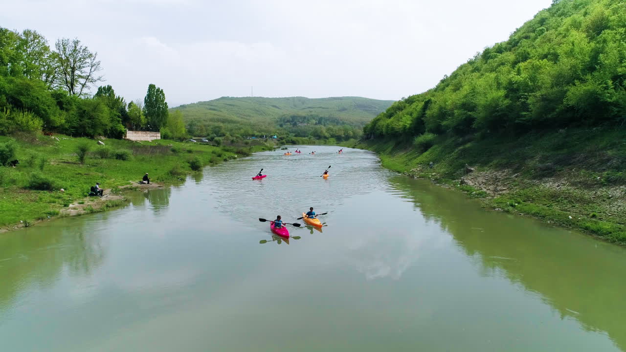 Gruppo di amici in kayak verso l'inquadratura, ripresa aerea con allontanamento lungo il fiume Drin in Kosovo