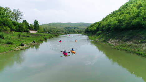 group of friends kayak towards frame, aerial pullback along river drin in kosovo