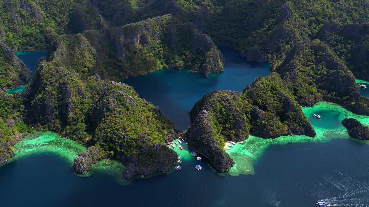 Azurblaues Wasser des Barracuda-Sees, umgeben von üppig grünen Kalksteinkarsten und vor Anker liegenden Booten entlang der Küste. Magische Drohnen-Panoramaaufnahme, die vorwärts fliegt.