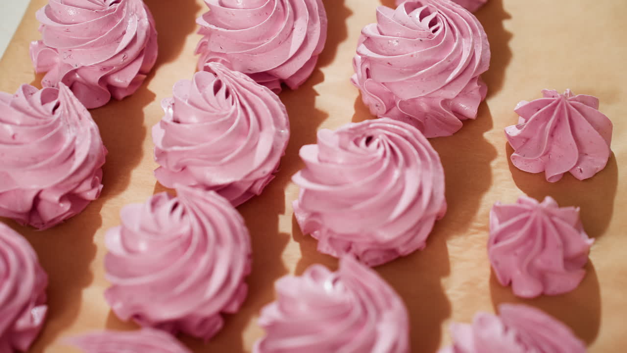 Beautiful display of neatly arranged swirl pink cupcakes on brown parchment paper with natural light highlighting smooth creamy texture, ready for baking