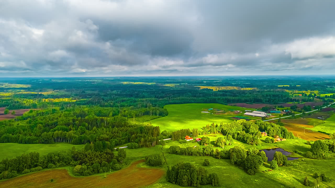 Lush green forests and fields under clouds casting shadows, creating a dynamic natural landscape