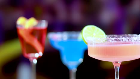 colorful cocktails with lime garnish in a lively bar atmosphere, featuring dynamic lighting and vibrant hues