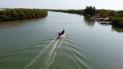 drone flying past speeding local fishing boat sailing on river gambia, kartong