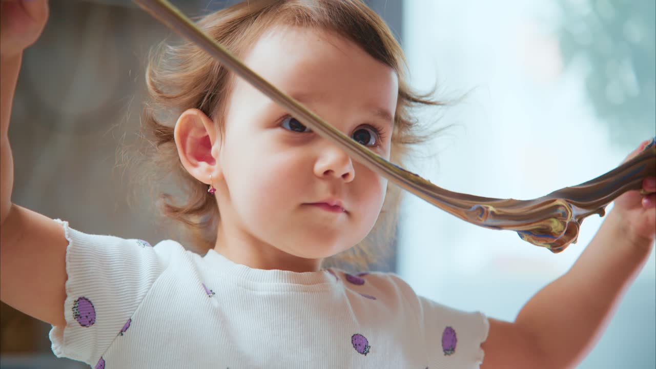 A Joyful Little Girl Engaged in Playful Exploration, Discovering Colorful Textures and Shapes with Curiosity in a Bright and Warm Indoor Setting