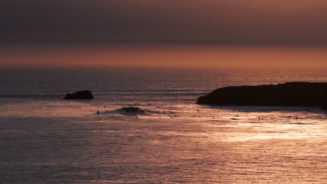 Drone-aerial-view-of-perfect-sunset-waves-and-surfers-in-the-water-waiting